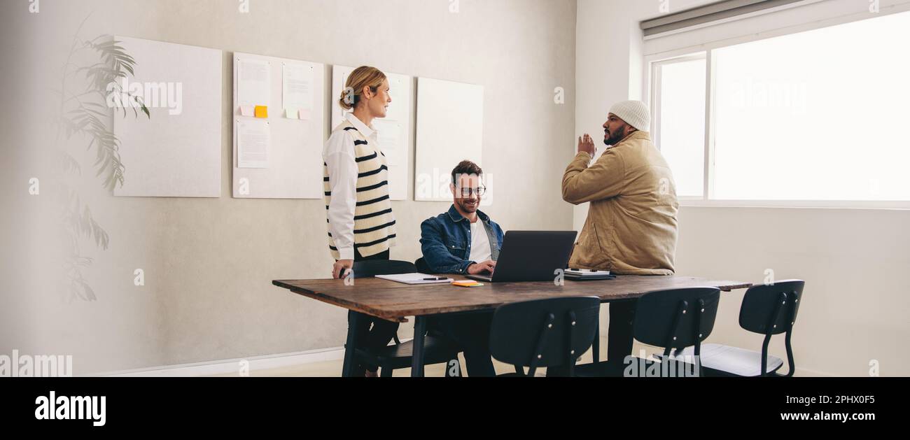 Groupe de divers hommes d'affaires ayant une discussion tout en travaillant ensemble dans un bureau créatif. Trois collègues d'affaires partagent leurs idées dans un W moderne Banque D'Images