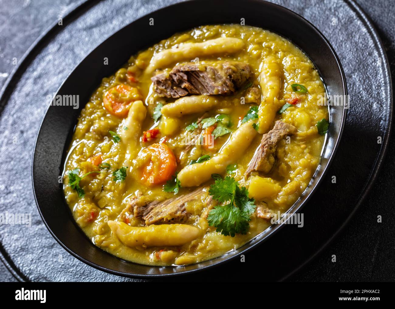 petits pois, soupe de petits pois avec boulettes et bœuf dans un bol noir sur table en béton, cuisine jamaïcaine, gros plan Banque D'Images