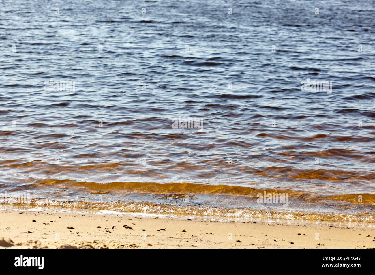 Bord de l'eau sur la rive. Vague de mer bleue sur une plage de sable. Magnifique fond avec des jets d'eau sur la plage Banque D'Images