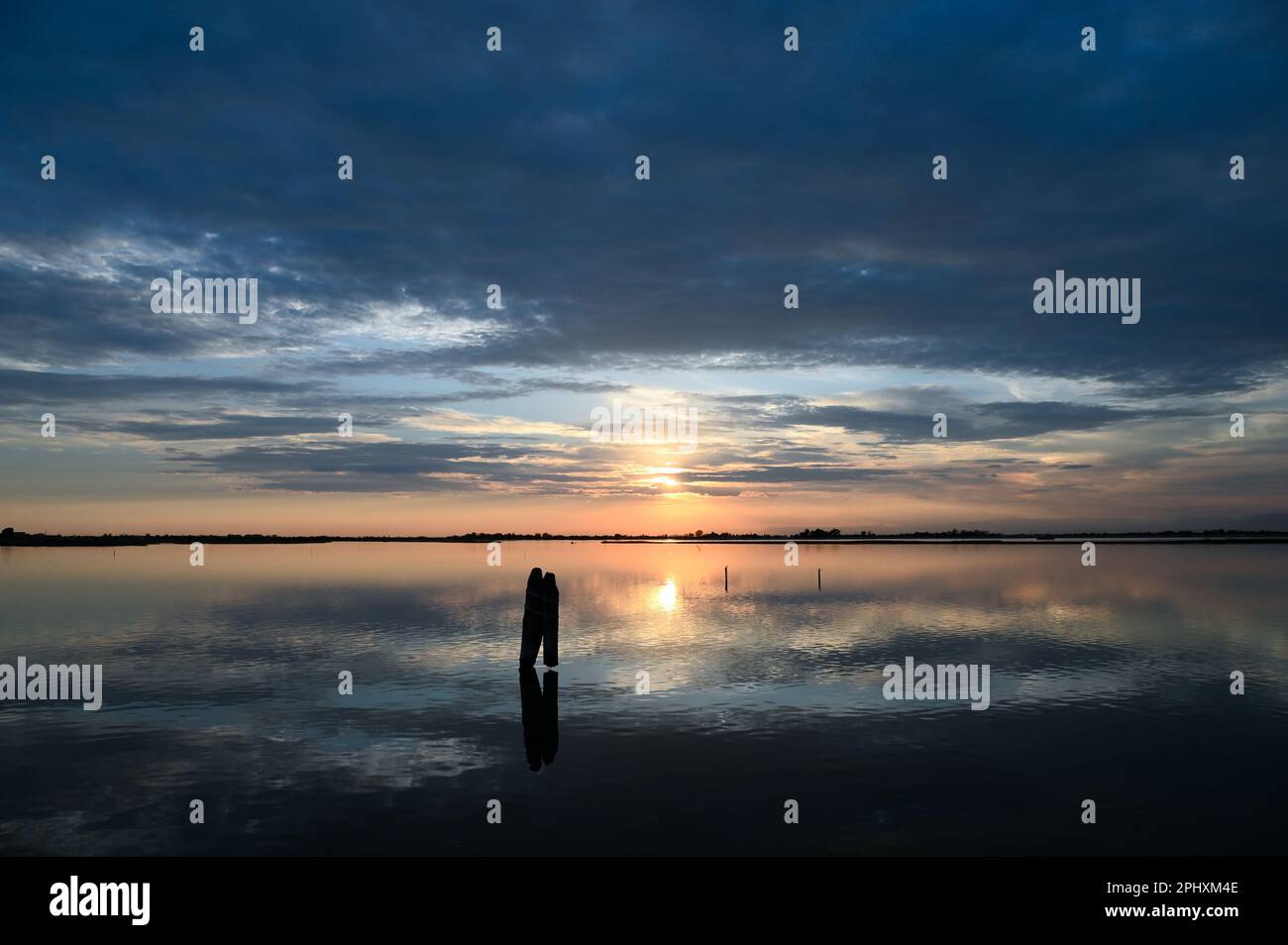 Vue pittoresque sur l'eau de mer calme reflétant le ciel nuageux au coucher du soleil en soirée paisible Banque D'Images