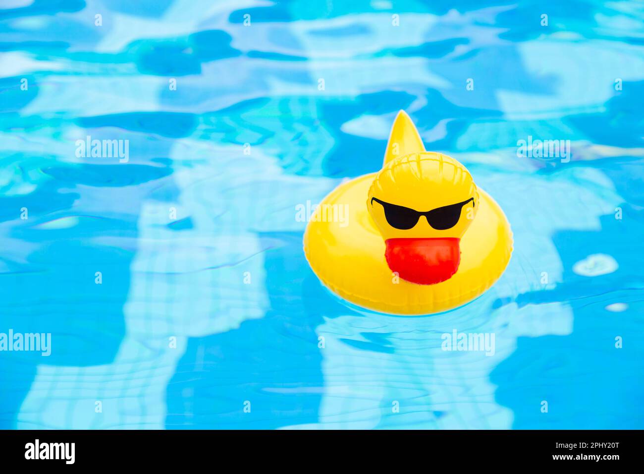 Anneau gonflable de canard flottant dans la piscine. Canard en plastique jaune avec lunettes de soleil Banque D'Images