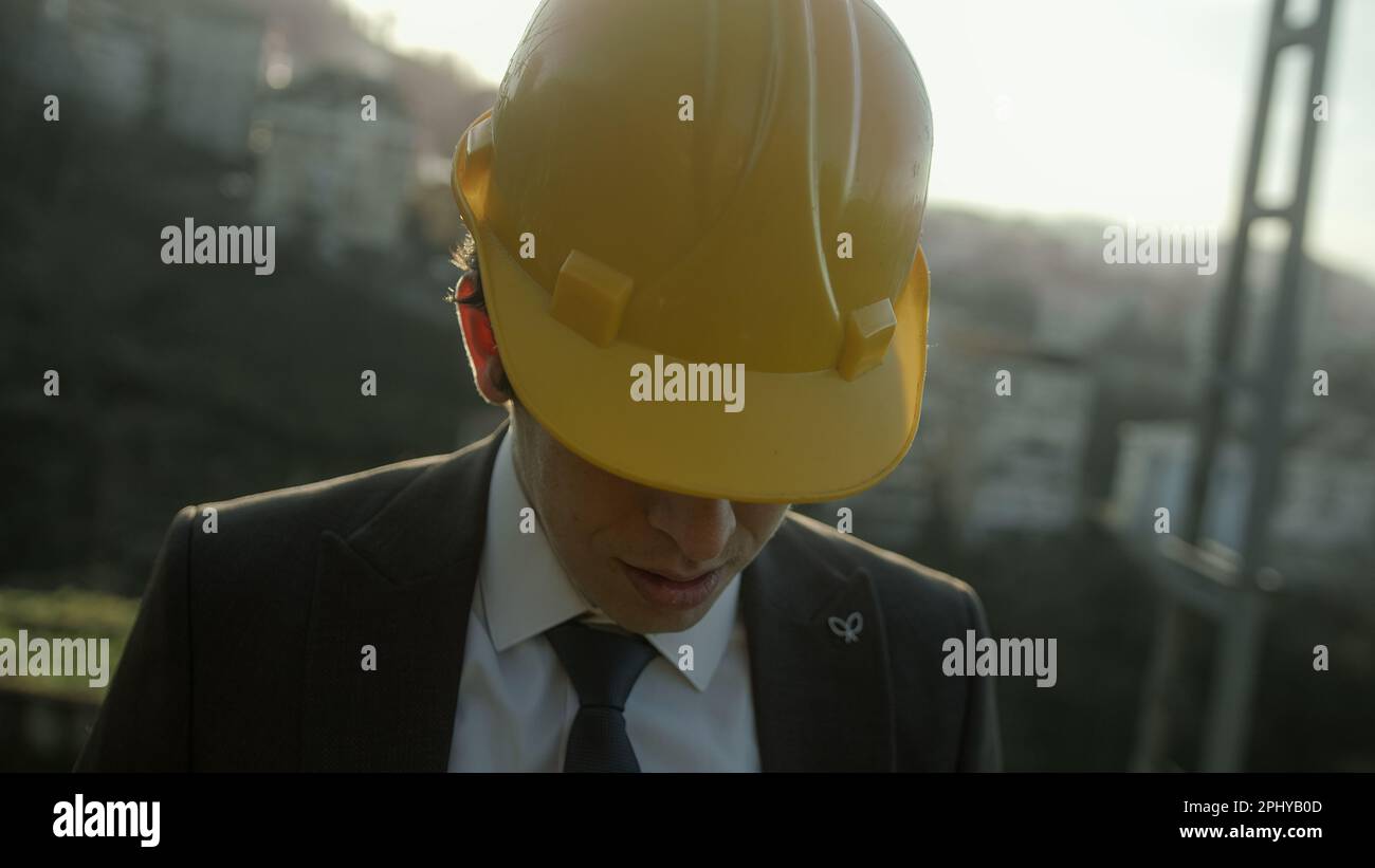 Jeune homme d'affaires ou ingénieur dans un Beret regardant vers le bas, le concept d'inconduite professionnelle Banque D'Images