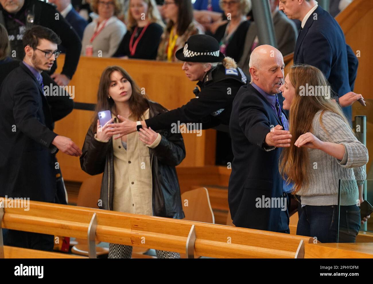 Les policiers et les agents de sécurité retirent les manifestants de la chambre lors des questions des premiers ministres (FMQ) au Parlement écossais à Holyrood, Édimbourg. Date de la photo: Jeudi 30 mars 2023. Banque D'Images
