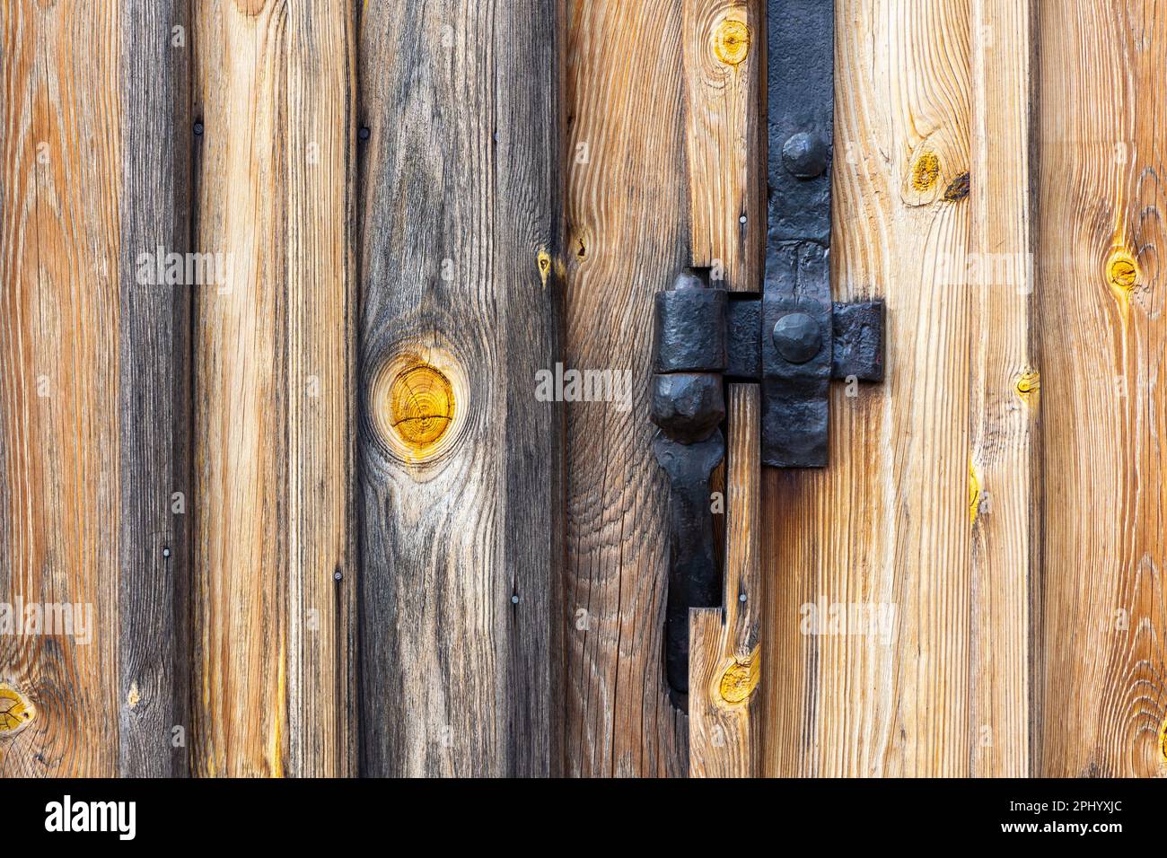 Anciens raccords de charnière noirs fabriqués par un forgeron. Raccords installés sur une ancienne porte en bois d'un ancien hangar Banque D'Images