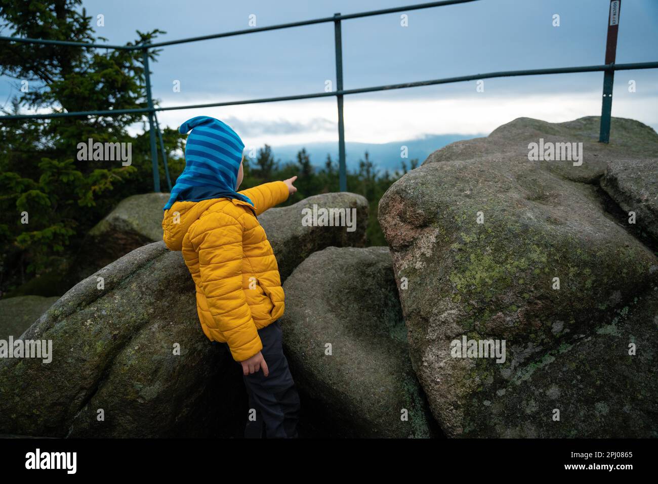 L'enfant se tient entre les blocs et pointe vers quelque chose au loin. Montagnes polonaises Banque D'Images
