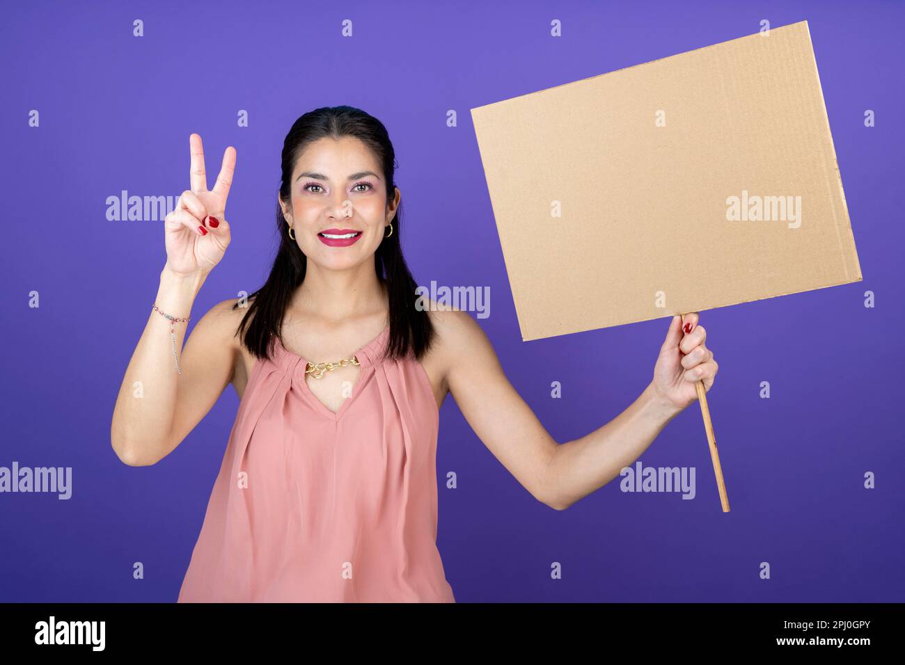 une jeune femme adulte tient une bannière dans sa main pour faire le symbole de paix et d'amour Banque D'Images