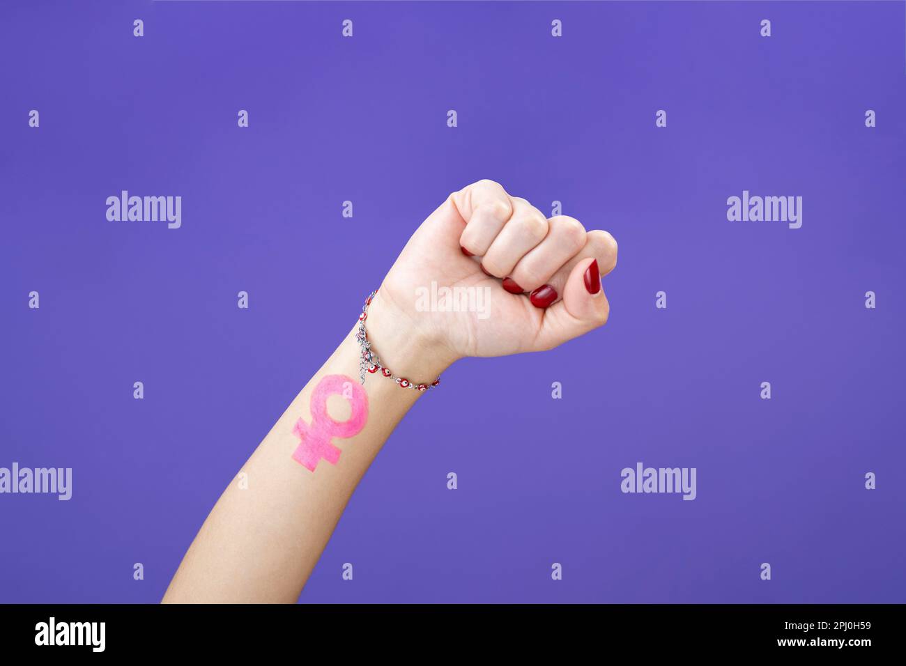 le poing de la femme se rapproche du symbole féministe sur un fond de velours violet isolé Banque D'Images