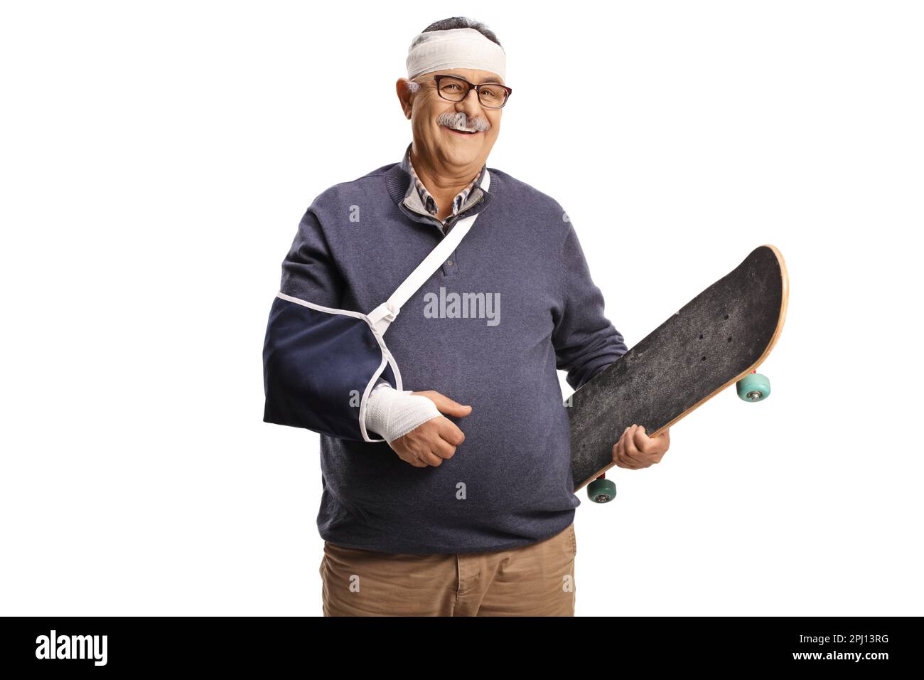 Homme mature avec un bras cassé et un bandage sur la tête tenant un skateboard et souriant isolé sur fond blanc Banque D'Images