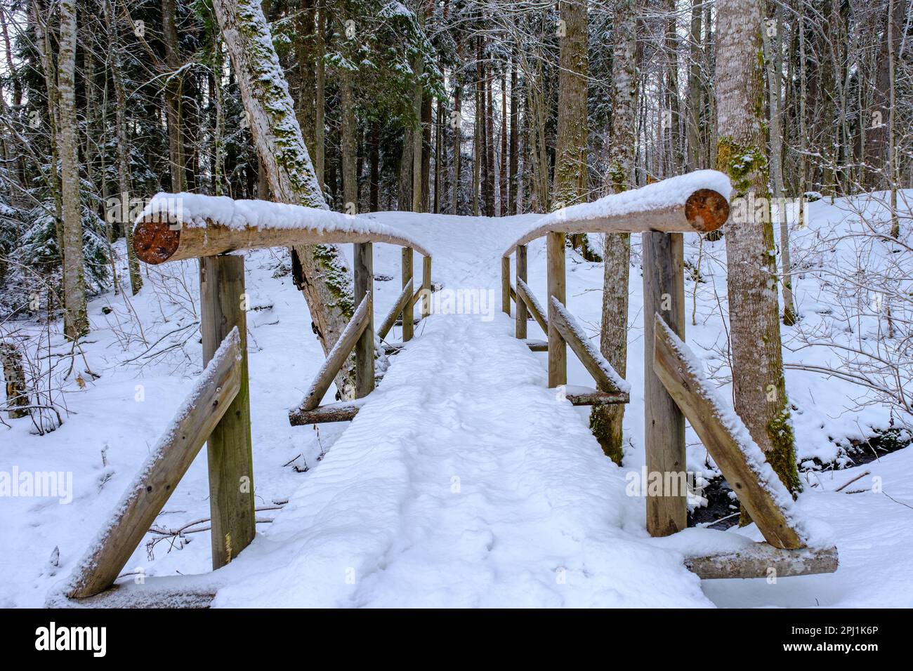 Pont en bois recouvert de neige au-dessus d'une petite rivière Banque D'Images