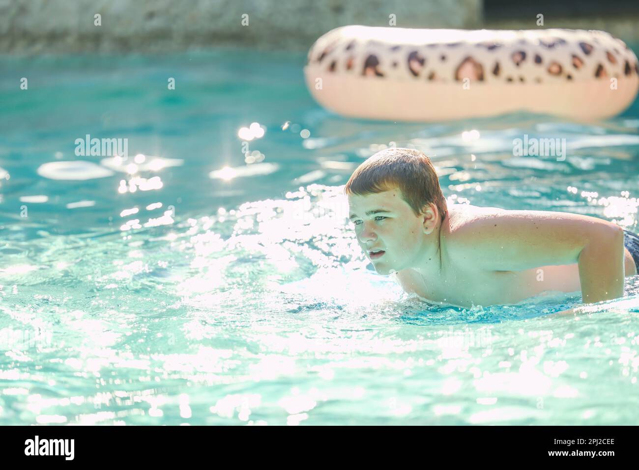 Un adolescent nageant sur le boogie board dans la piscine de l'arrière-cour Banque D'Images