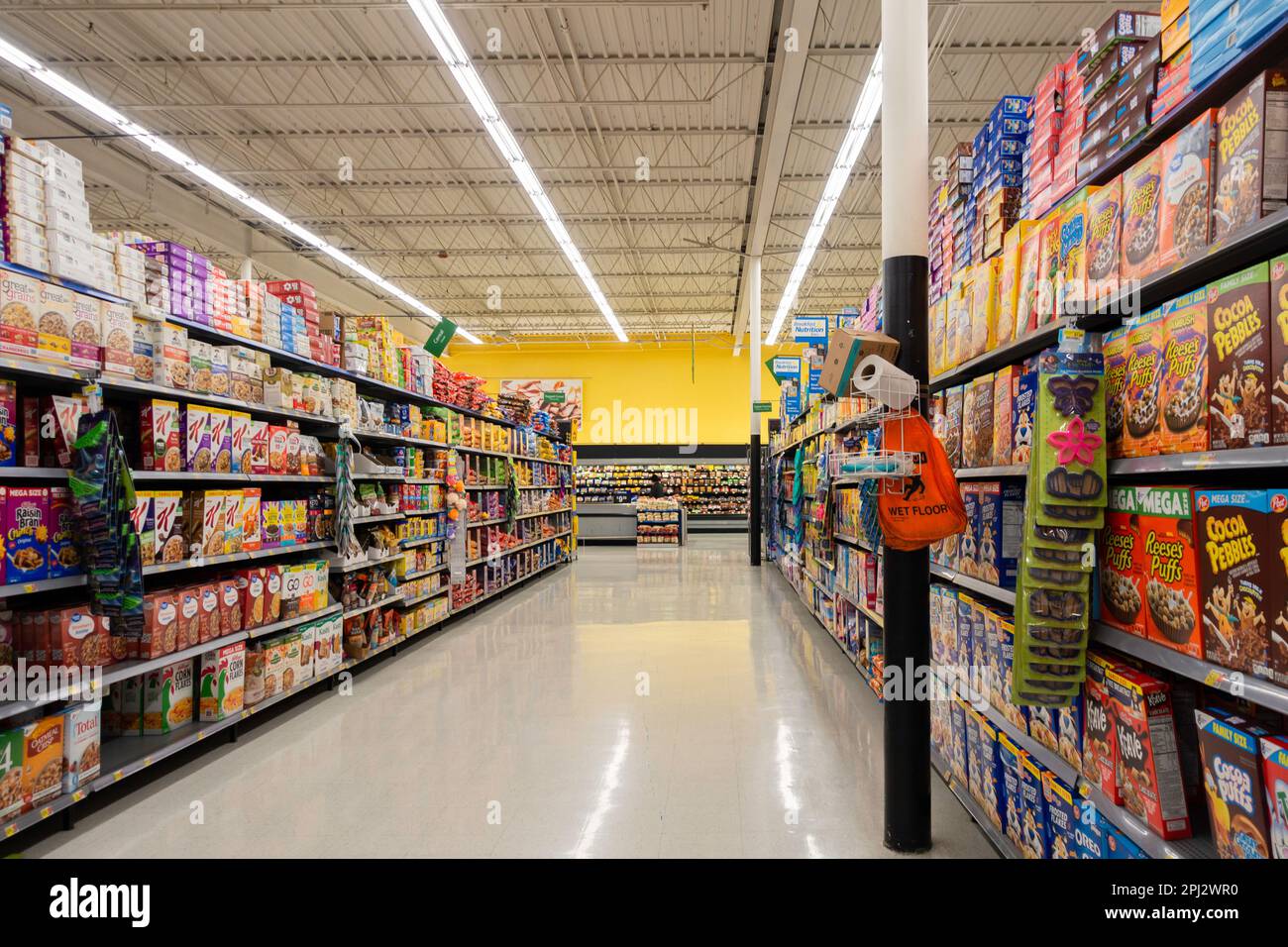 Une femme lointaine qui a marché des produits à la fin de l'allée de céréales en boîte dans un supermarché Walmart à Wichita, Kansas, États-Unis. Banque D'Images