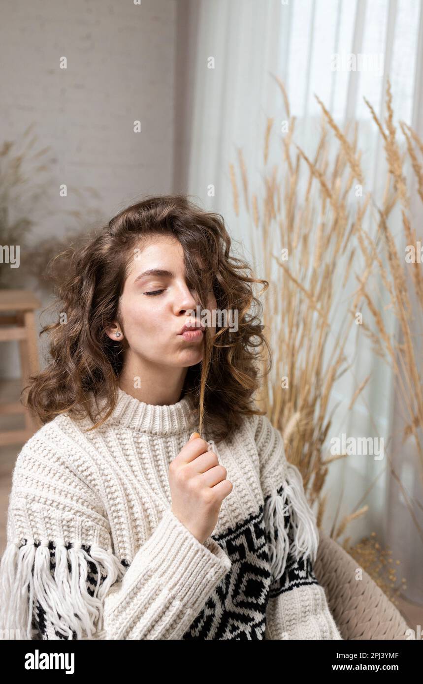 photo d'une jeune fille adolescente attrayante, une jeune femme aux cheveux bouclés, vêtue d'un pull chaud, lèvres pliées sous forme de baiser d'air. mystérieux, dre Banque D'Images