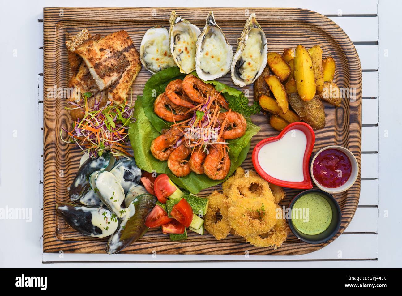 Beaucoup de fruits de mer comme poisson frit, calamars, huîtres et sauces sur bois sur la table Banque D'Images