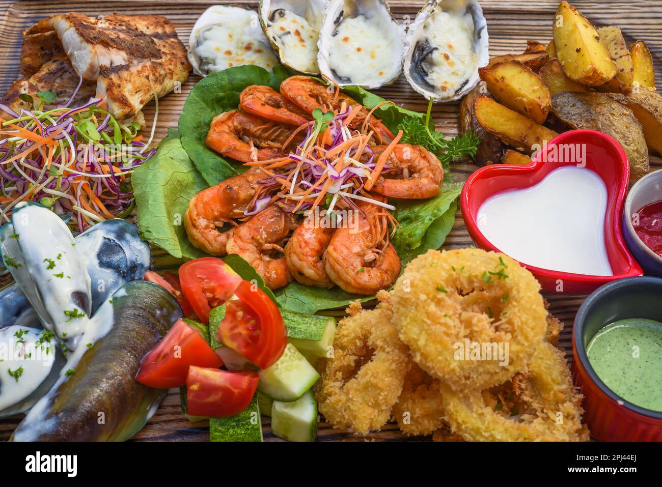 Beaucoup de fruits de mer comme poisson frit, calamars, huîtres et sauces sur bois sur la table Banque D'Images