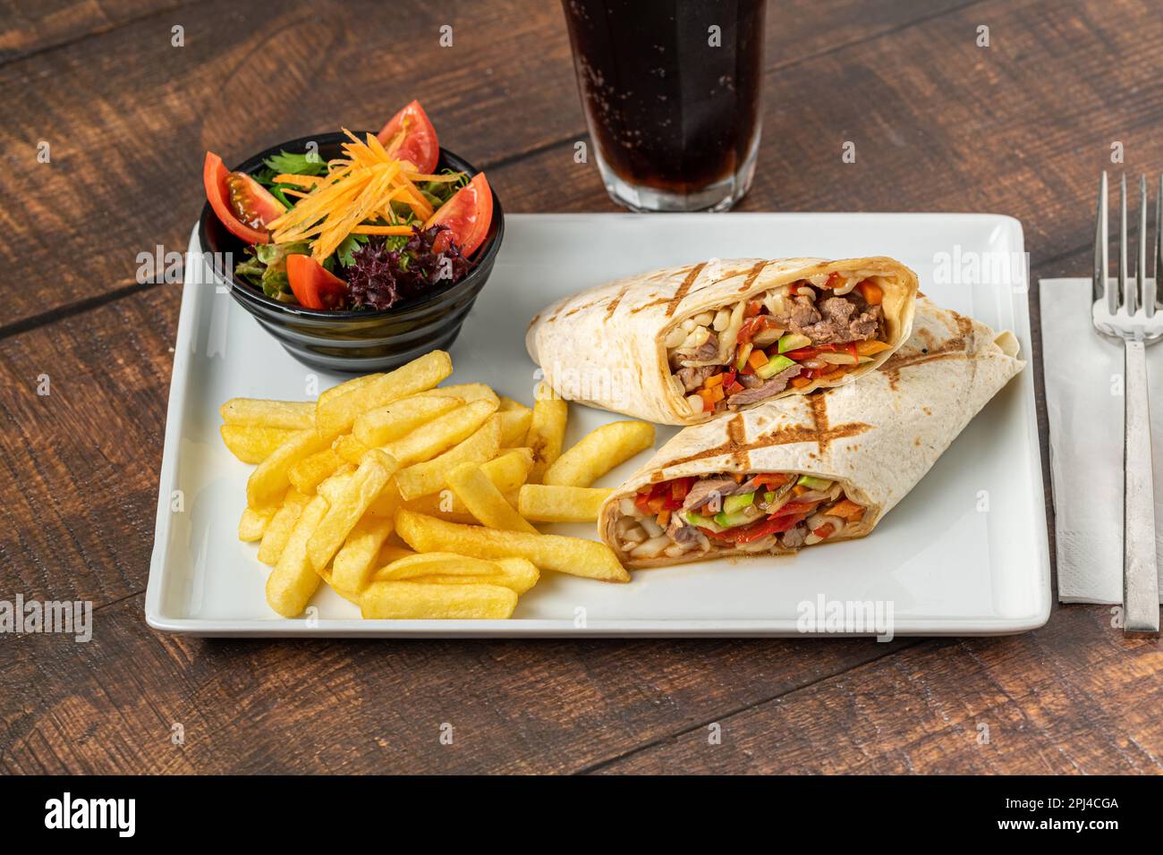 Emballage de viande coupé en deux avec des frites sur une table en pierre sombre Banque D'Images