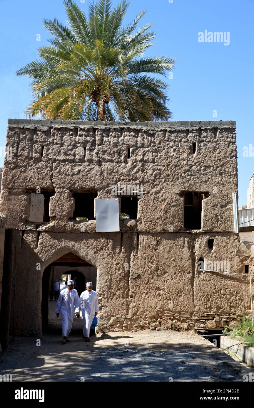 Oman, Birkat al Mawz: entrée au village de bâtiments abandonnés en briques au pied d'un affleurement spectaculaire en pierre, entouré d'une mer d'andate Banque D'Images