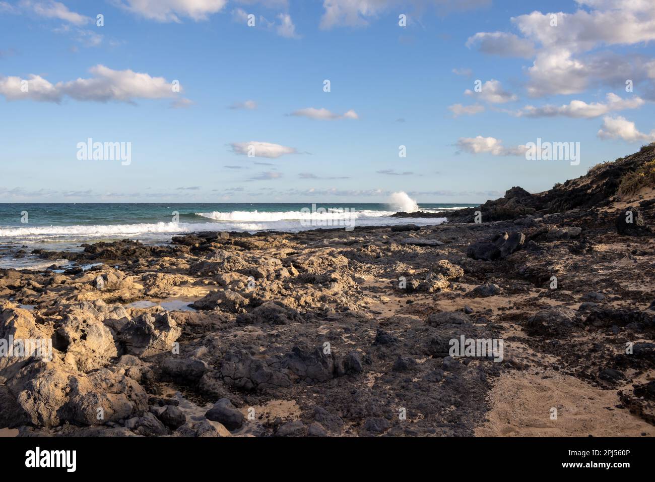 Combinaison d'un sable et d'une côte rocheuse à la plage de l'océan Atlantique. Ciel bleu avec nuages blancs. Parque Natural Dunas de Corralejo, Fuerteventura, SP Banque D'Images