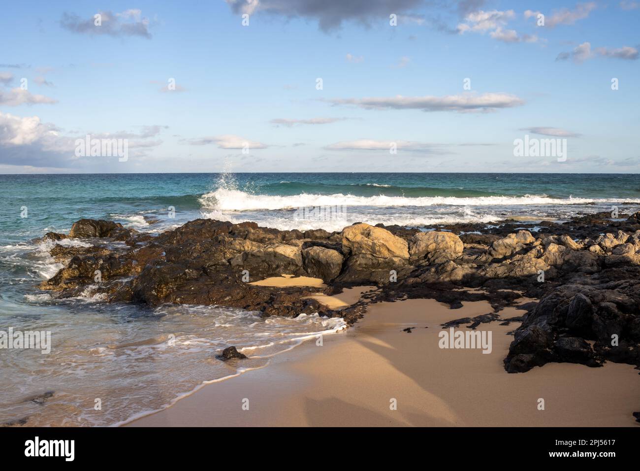 Combinaison d'un sable et d'une côte rocheuse à la plage de l'océan Atlantique. Ciel bleu avec nuages blancs. Parque Natural Dunas de Corralejo, Fuerteventura, SP Banque D'Images