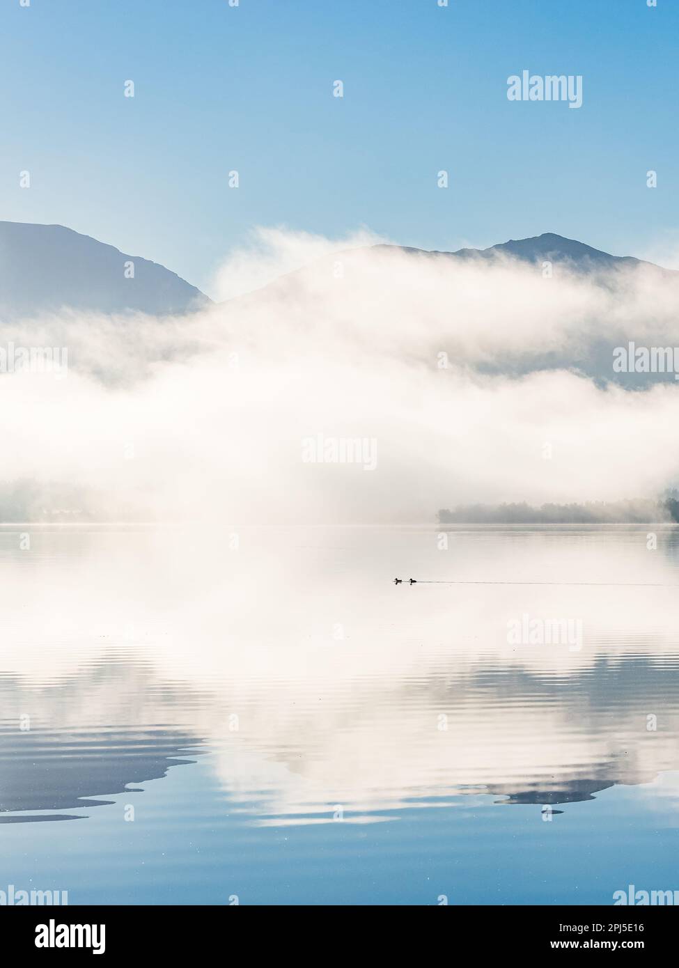 Une scène matinale sereine et tranquille en Norvège d'un lac fixe reflétant les montagnes, le brouillard, le ciel et les nuages créant un paysage idyllique de beauté. Banque D'Images