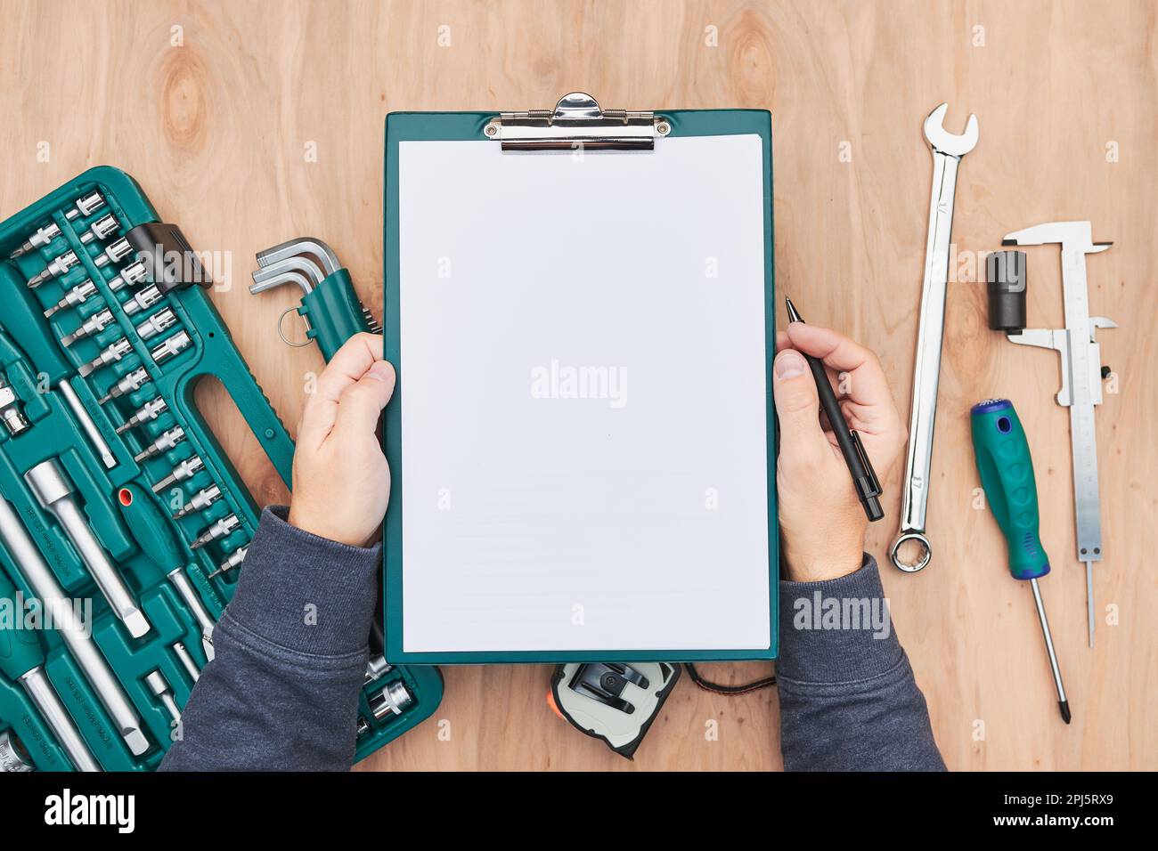 Homme travaillant dans un atelier tenant le presse-papiers à l'aide de nombreux outils. Clé, clé, étrier et cliquet avec de nombreux accessoires. Outils de travail. Outil universel se Banque D'Images