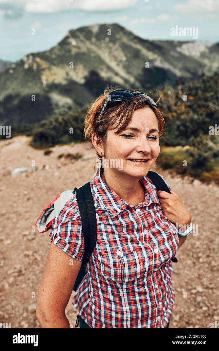 Souriante femme heureuse avec sac à dos de randonnée dans une montagne, de passer activement des vacances d'été, de marcher sur une colline, debout sur le chemin de montagne par mugo pi Banque D'Images