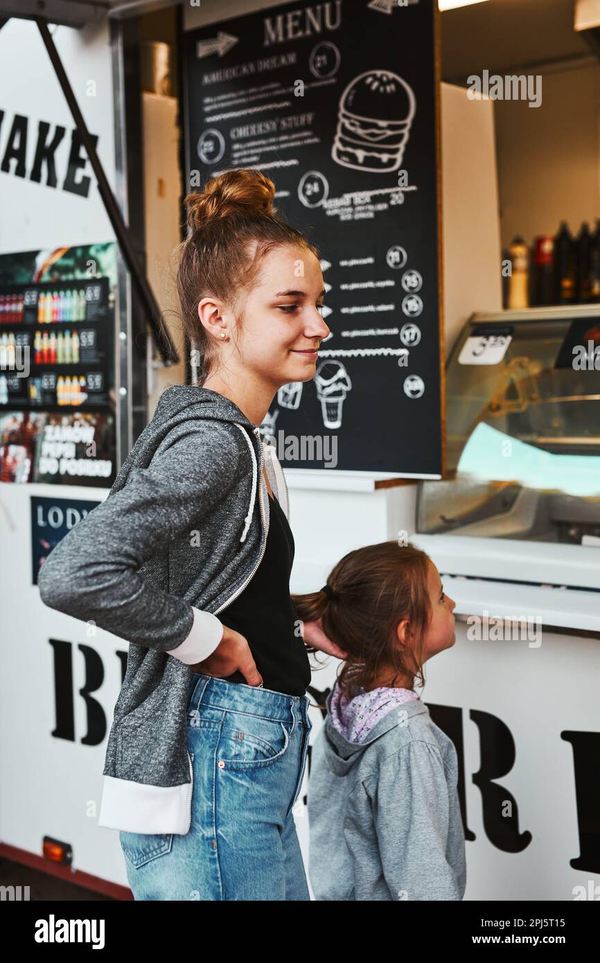 Une adolescente et sa jeune sœur attendent leur commande devant un camion pendant les vacances d'été Banque D'Images