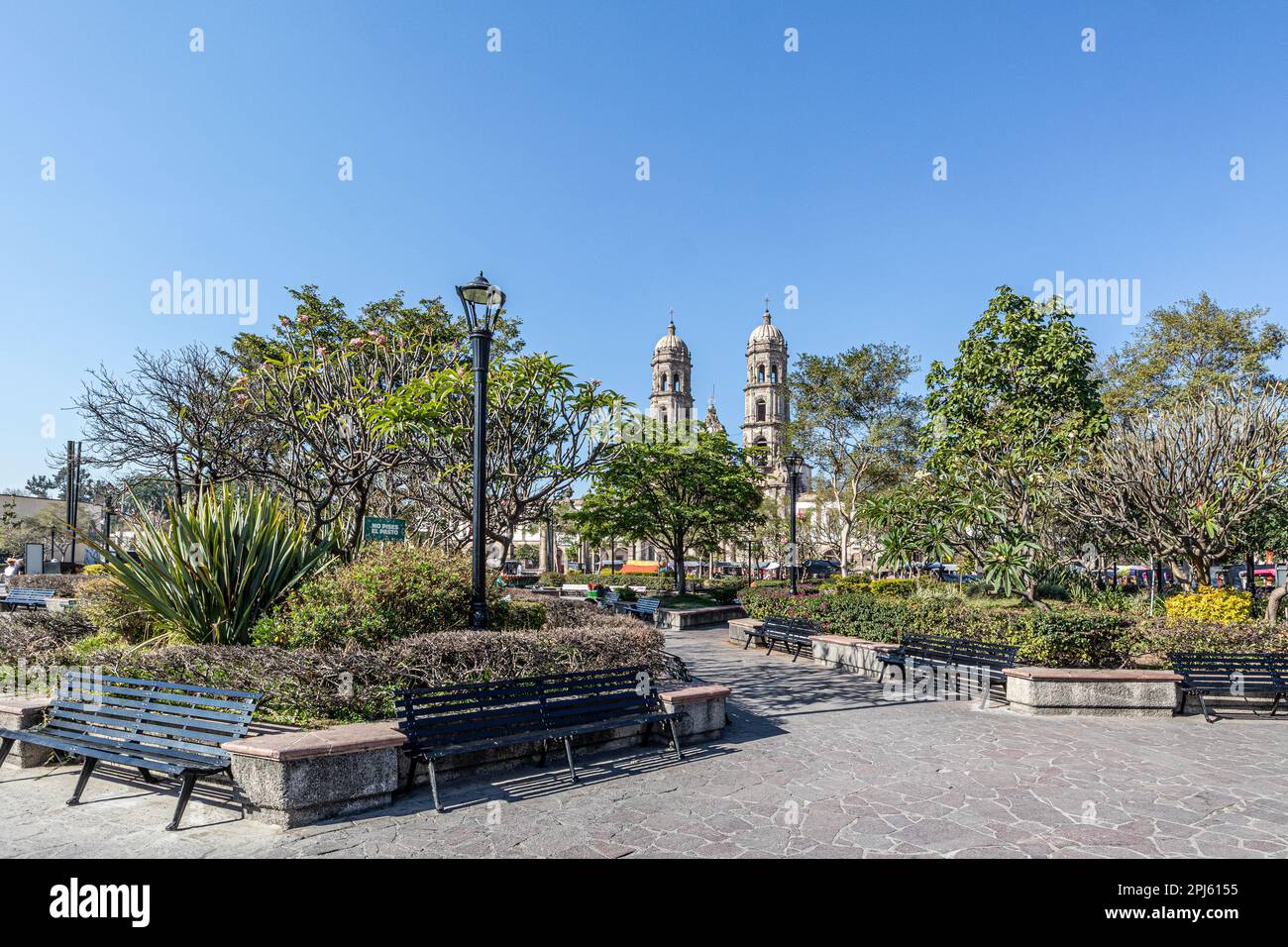 Plaza de las Americas avec des arbres verts et des chemins piétonniers contre le ciel bleu, Basilique de notre Dame de Zapopan en arrière-plan, panneau: Garder de l'herbe, Banque D'Images