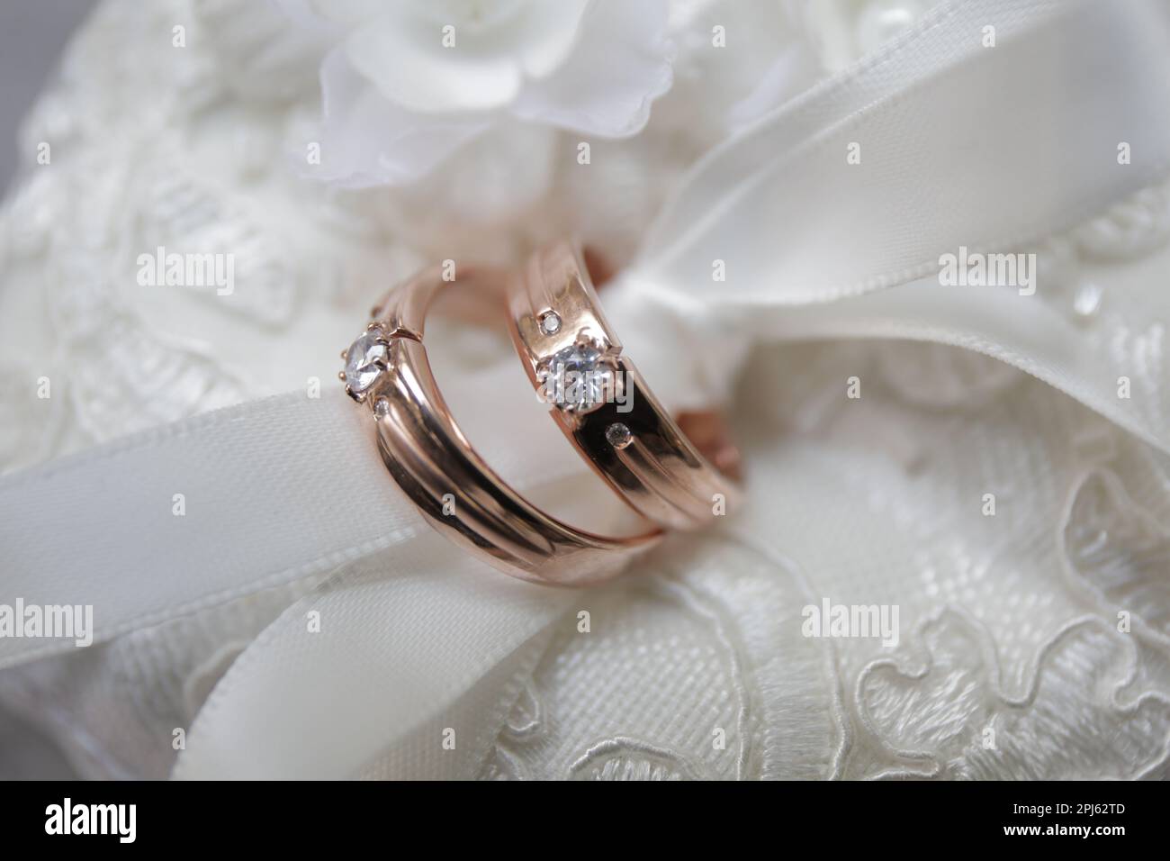 Paire d'anneaux de mariage or rose avec diamant attaché dans un tissu blanc Banque D'Images