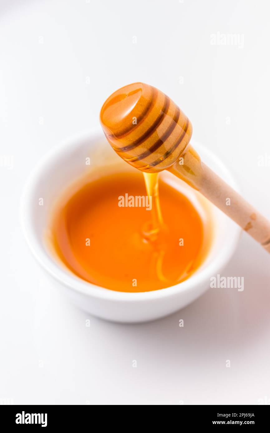 Miel avec un balancier de miel en bois sur fond blanc Banque D'Images