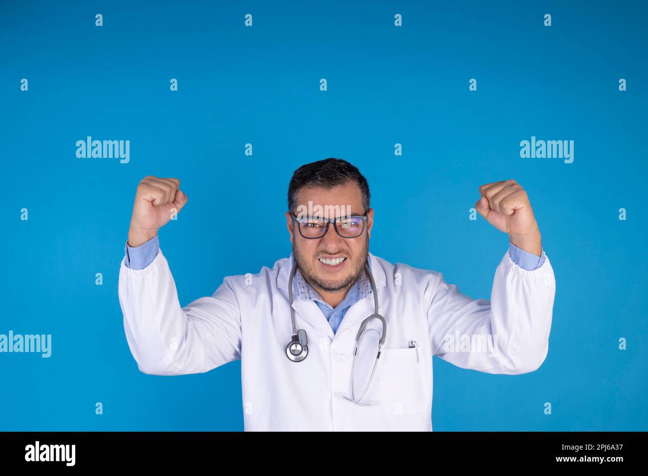 Joyeux médecin célébrant parce qu'il a guéri ses patients sur un fond bleu isolé. Banque D'Images