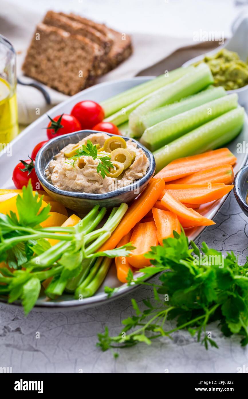 Assiette de légumes frais assortis avec sauce à l'avocat, houmous, champignons marinés et olives Banque D'Images