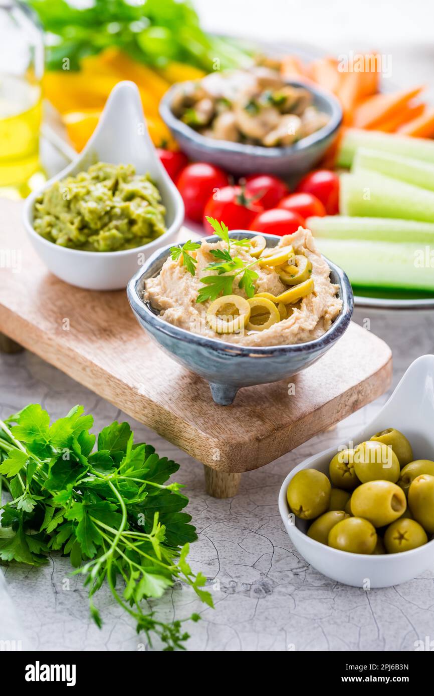 En-cas sains, trempez de l'humus et de l'avocat faits maison avec un assortiment de légumes frais et de champignons marinés Banque D'Images