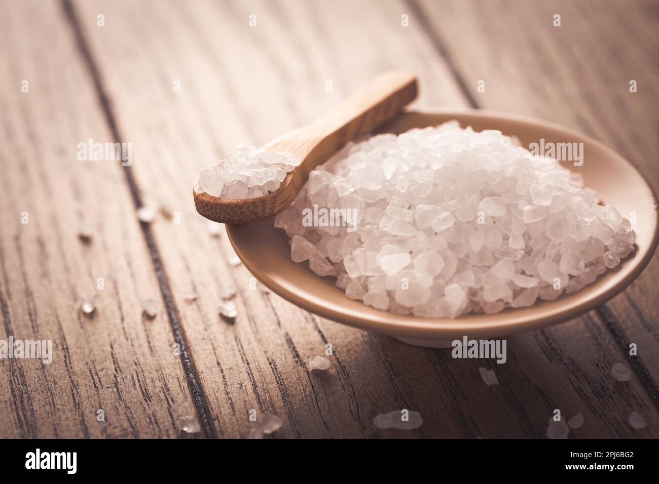 Sel blanc rocailloux dans un bol sur fond de bois Banque D'Images