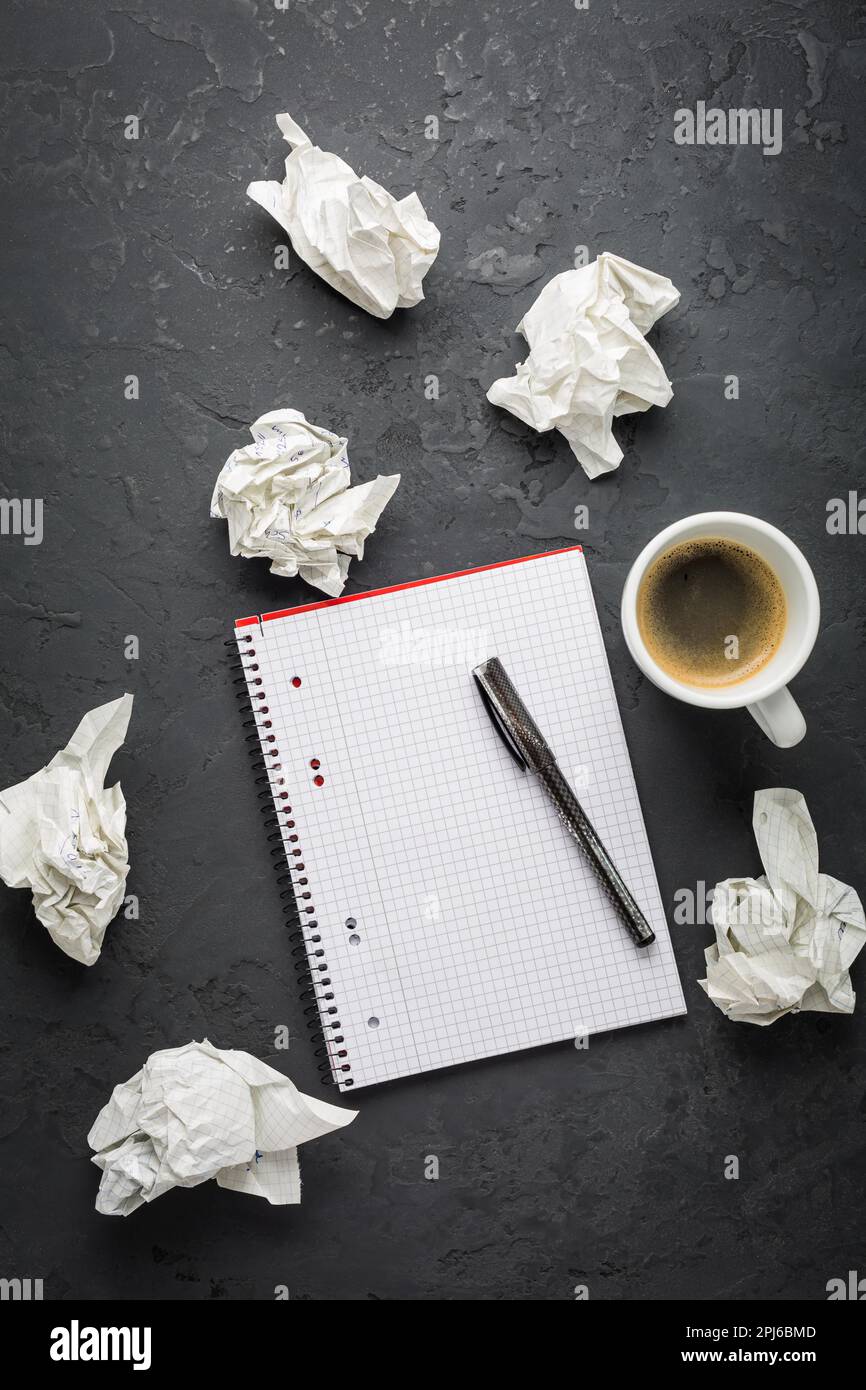 Espace de travail : tasse de café avec bloc-notes vide et stylo sur fond noir Banque D'Images