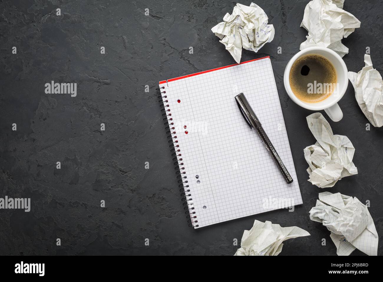Espace de travail : tasse de café avec bloc-notes vide et stylo sur fond noir Banque D'Images