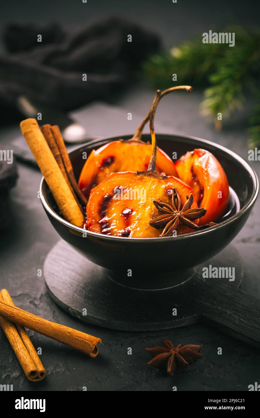 Dessert de Noël - tamarillo en mousse dans un punch au vin chaud avec de la cannelle et de l'anis sur fond noir Banque D'Images