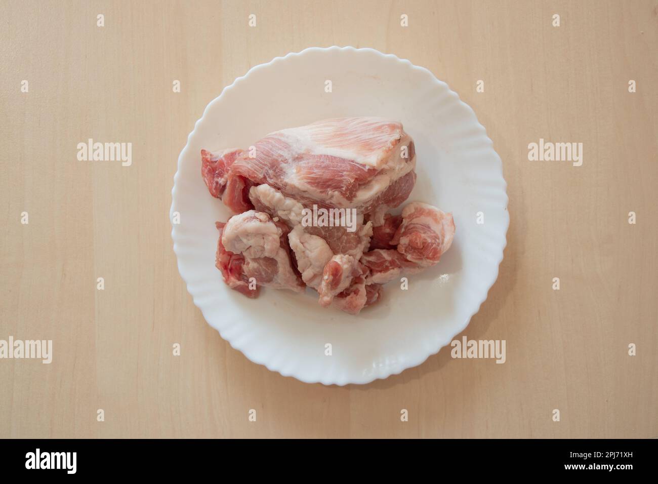 un morceau de porc cru se trouve dans une assiette blanche sur la table Banque D'Images