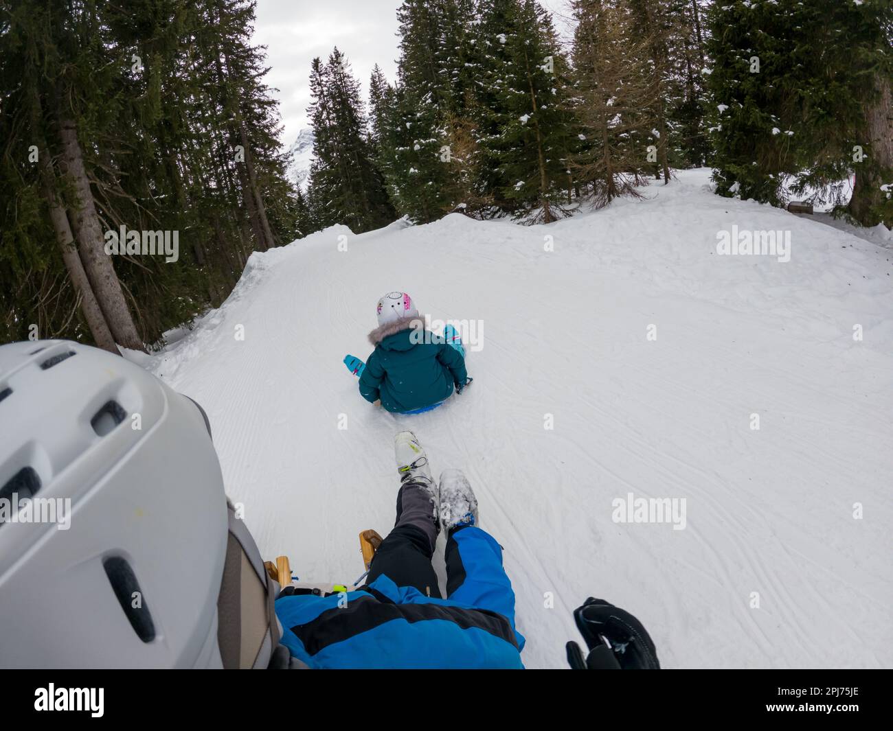 Point de vue d'un coureur s'amusant sur un traîneau à neige essayant d'attraper sa fille. Banque D'Images