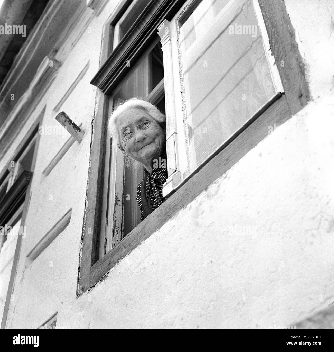 Sibiu Comté, Roumanie, environ 1976. Femme âgée regardant par la fenêtre de sa maison. Banque D'Images