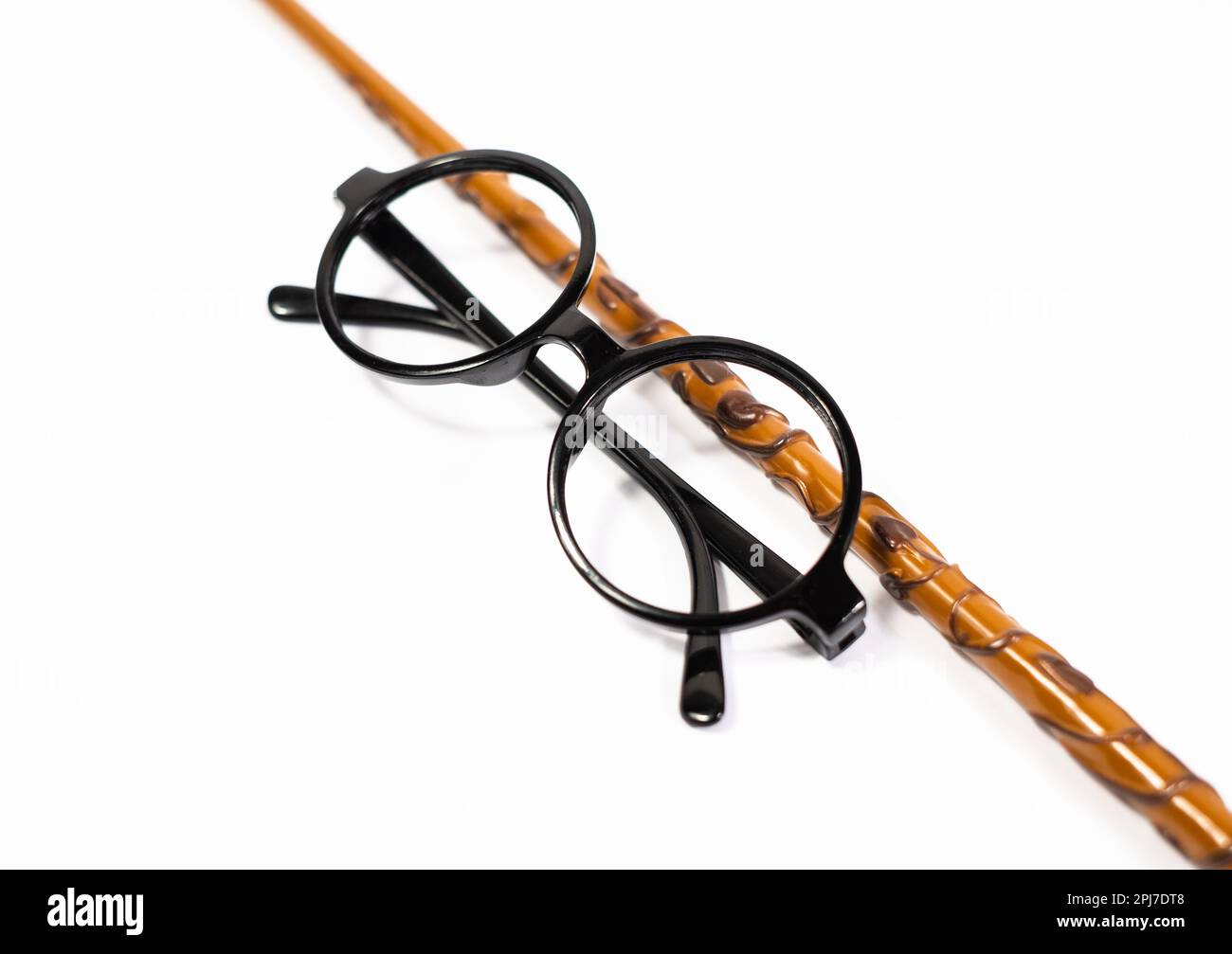 Lunettes noires rondes et baguette magique marron isolées sur fond blanc. Banque D'Images