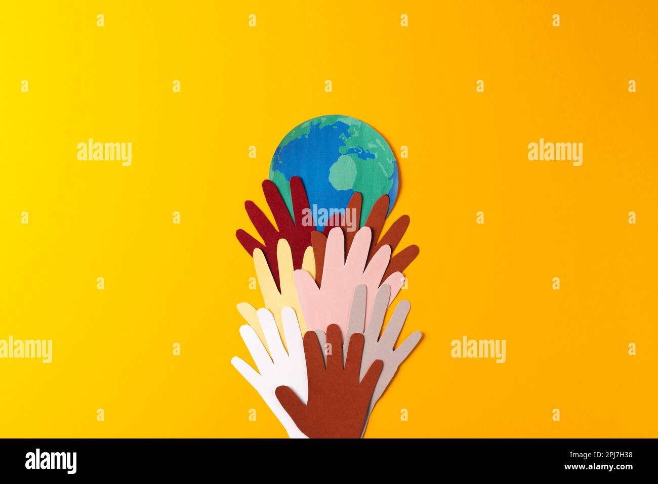 Papier découpé de mains et de globe multicolores avec espace de copie sur fond jaune Banque D'Images