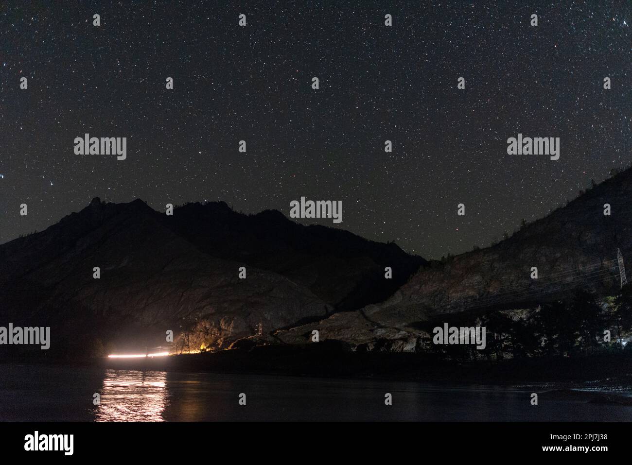 Sentier léger des phares d'une voiture la nuit sur une route de montagne sous les étoiles près de la rivière Katun en Altaï Banque D'Images