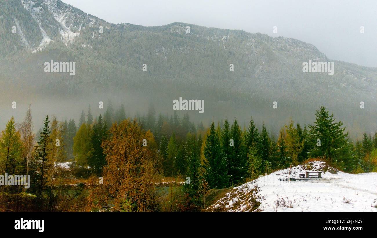 Un endroit pour se reposer avec un banc et un barbecue dans la neige au bord d'une falaise la nuit dans la brume des montagnes près de la forêt de l'Altaï. Banque D'Images