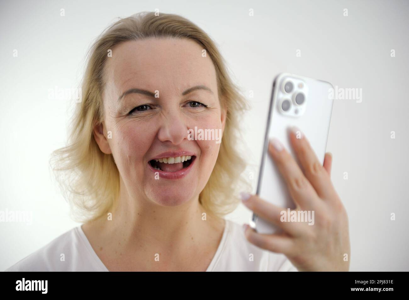 Belle femme tenant une maquette de smartphone d'écran vide et montre le signe ok sur fond gris. Photo de haute qualité Banque D'Images