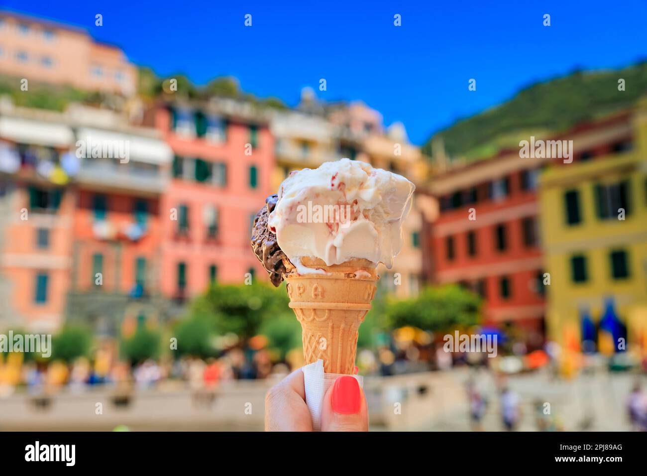 Main tenant une glace artisanale, une vue sur les maisons traditionnelles colorées dans la vieille ville de Vernazza dans les Cinque Terre sur la mer Méditerranée, Italie Banque D'Images