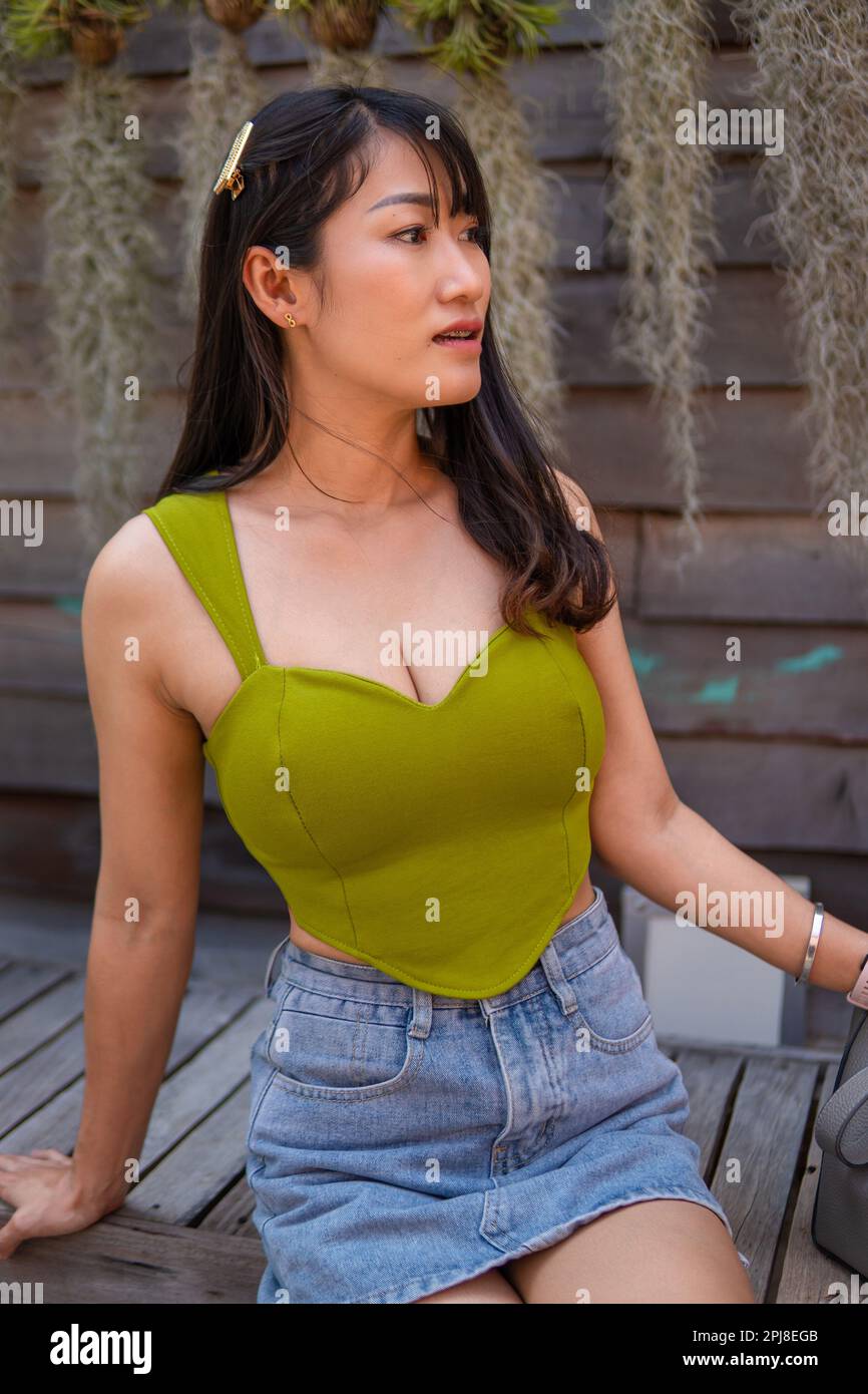 Portrait d'une belle femme asiatique sexy portant une robe verte sans bretelles et une jupe jean dans un café Banque D'Images