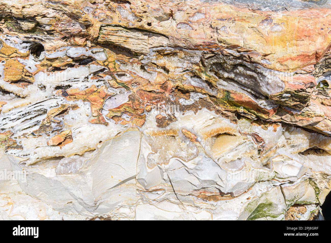 Formation de roche d'une falaise près de la mer dans les couleurs jaune, orange, blanc et vert. Banque D'Images