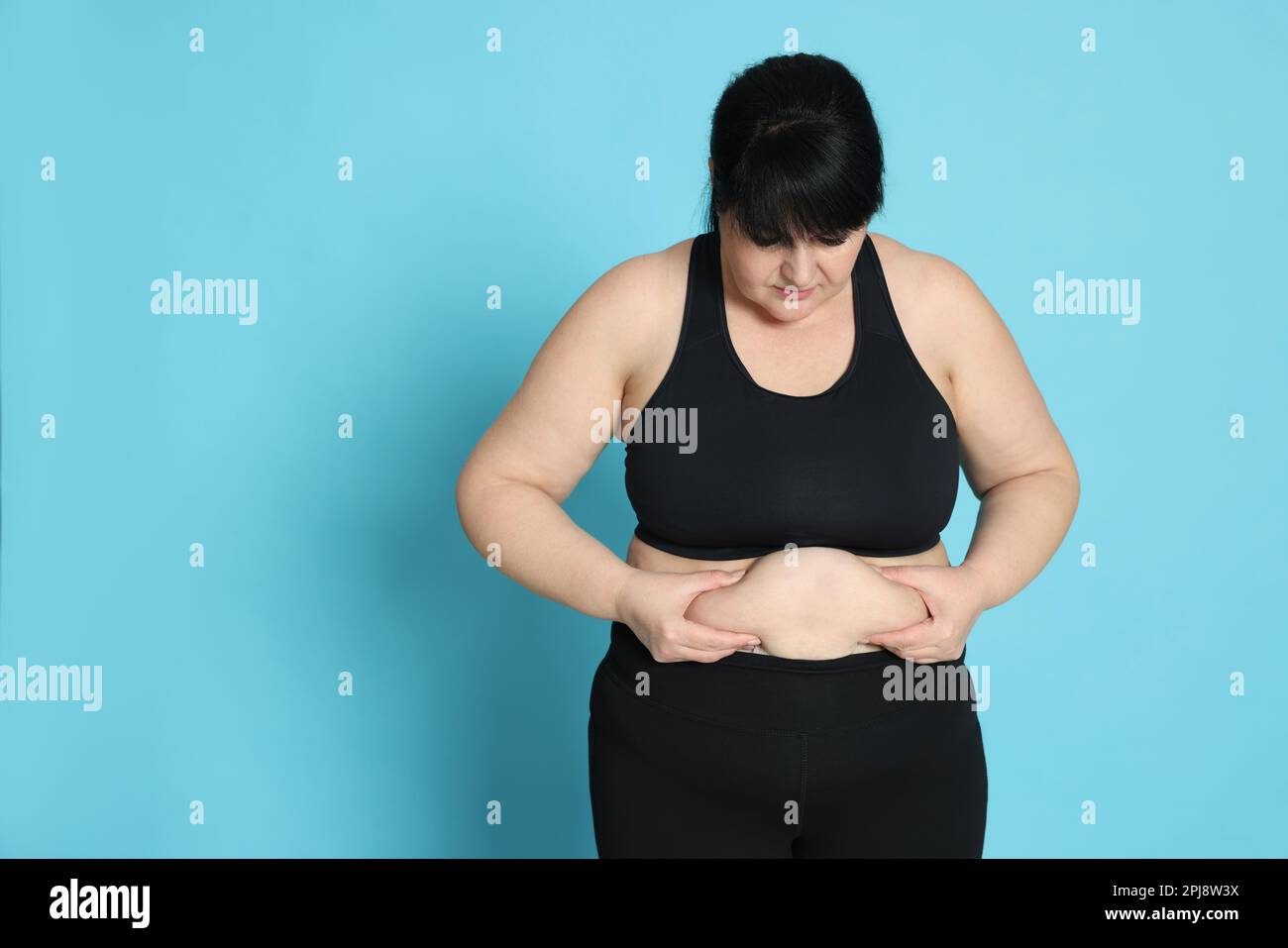 Femme obèse sur fond bleu clair. Chirurgie de perte de poids Banque D'Images