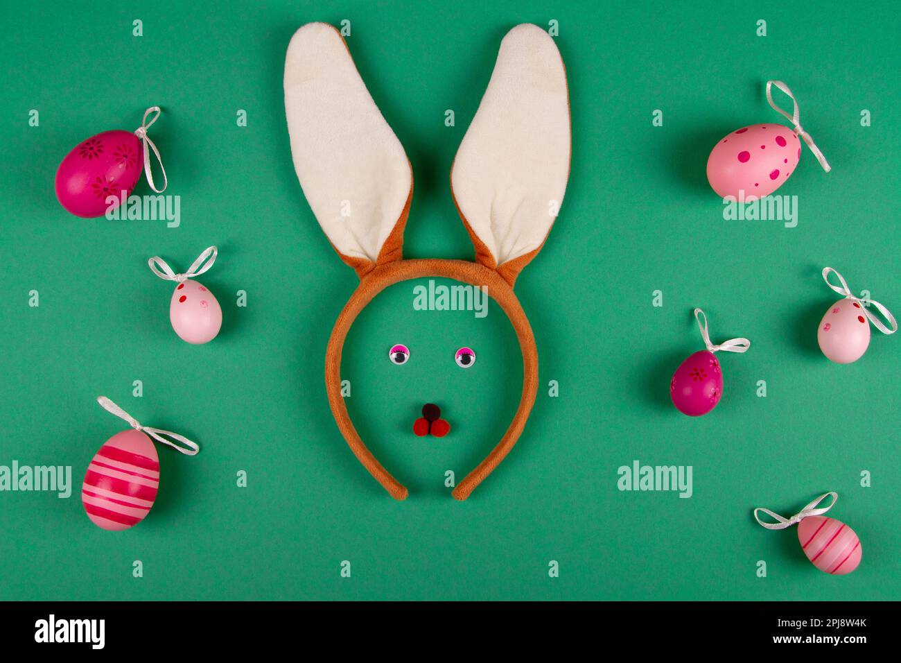 Décor vert humoristique sur le thème de Pâques orné d'œufs roses et d'un petit lapin Banque D'Images