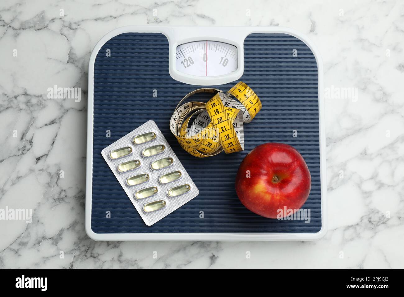Balance avec capsules d'huile, pomme et mètre ruban sur table en marbre  blanc, vue du dessus. Perte de poids Photo Stock - Alamy